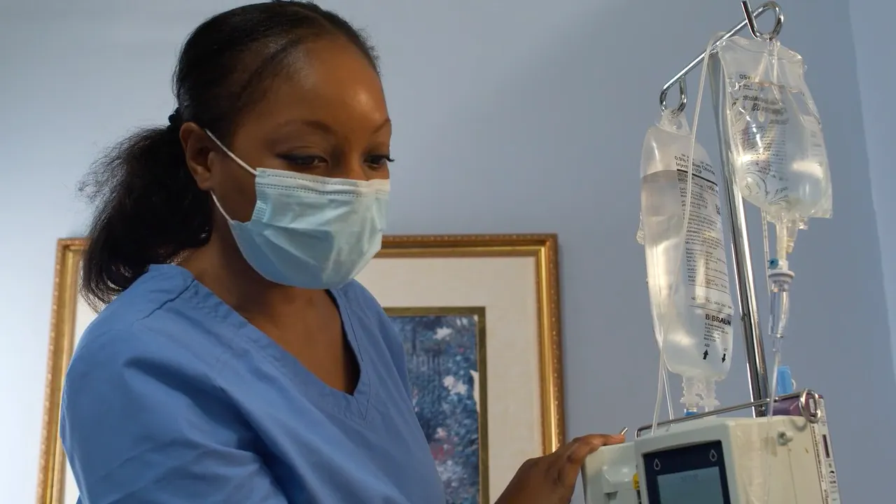 A nurse in blue scrubs and a face mask at work