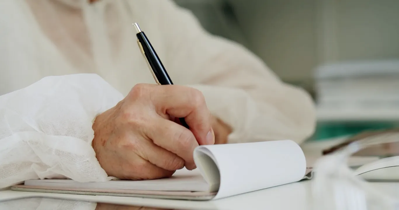 A hand writing notes in a small notepad